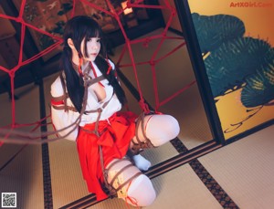 A woman in a red and white outfit is tied up with ropes.