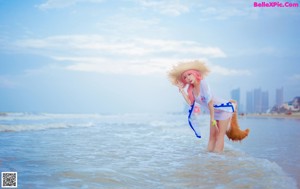 A woman in a straw hat is sitting in the water.