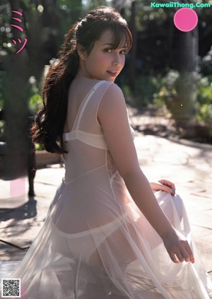 A woman in a white dress sitting on a bench.