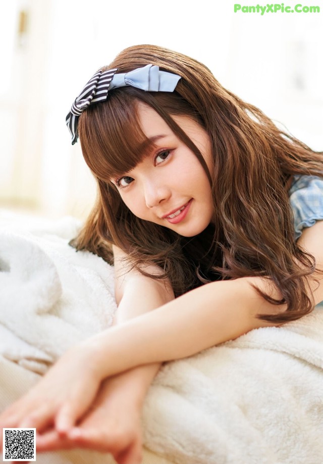 A young woman laying on top of a white blanket.