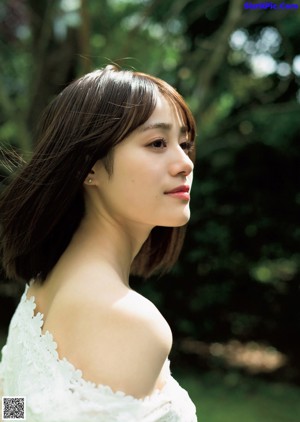 A woman in a black tank top leaning against a wall.