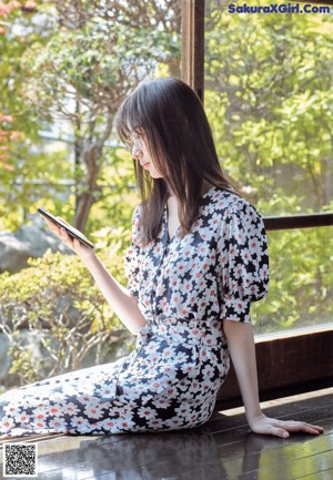 A woman sitting on a bench looking at a tablet.