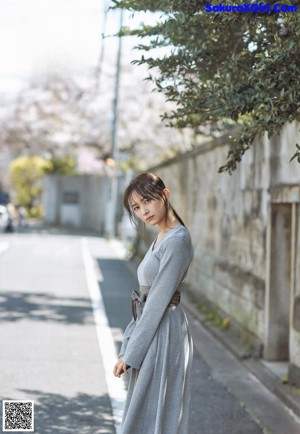 A woman with long black hair standing in front of a wall.