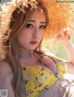 A woman in a white bikini standing in a grassy field.