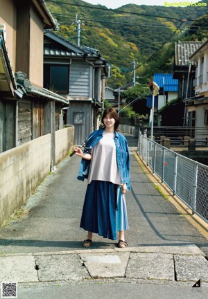 A woman standing in the middle of a street with her hands up.