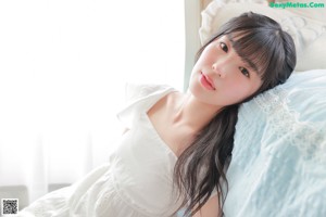 A woman laying on a bed in a white dress.