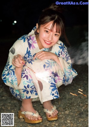 A woman in a kimono holding a sparkler in her hand.