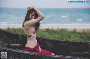 A naked woman standing in front of a stone wall.
