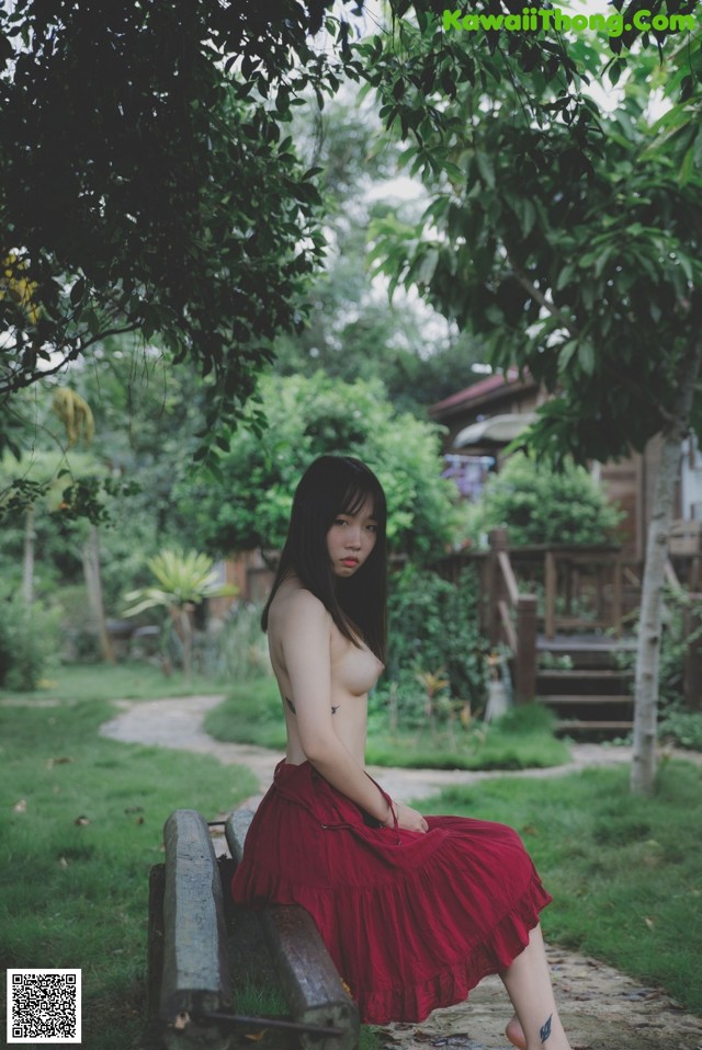 A woman in a red skirt sitting on a bench.