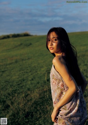 A woman in a floral dress standing in a field.