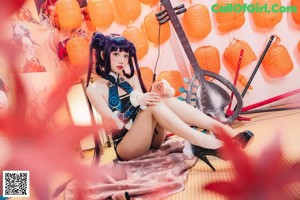 A woman sitting on the floor next to a guitar.