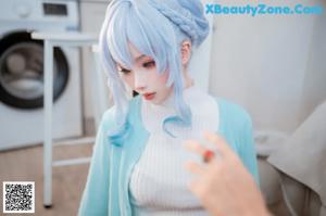 A woman in a blue and white outfit standing in a kitchen.