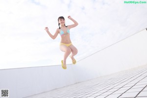 A woman in a bikini sitting on a tiled floor.