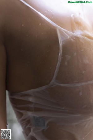 A naked asian woman standing in a bathtub holding a white shirt.