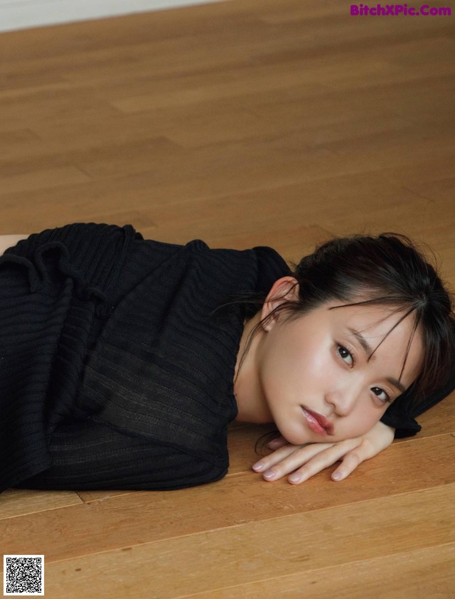 A woman laying on the floor with her head resting on her hands.