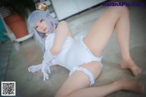 A woman in a white lingerie sitting on a chair.