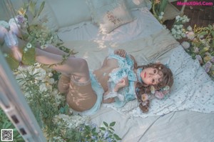 A woman in lingerie sitting on a bed surrounded by flowers.