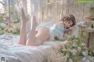 A woman sitting on a bed surrounded by flowers.