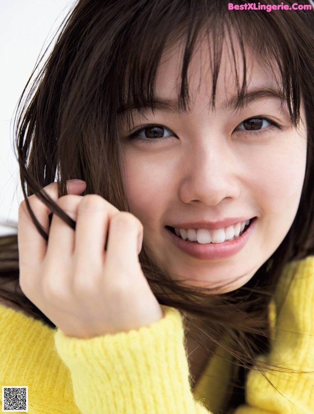 A woman in a yellow sweater smiles at the camera.