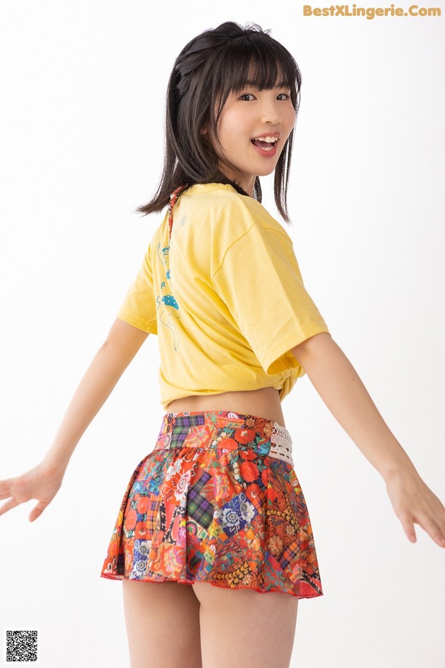 A young woman wearing a yellow shirt and a colorful skirt.