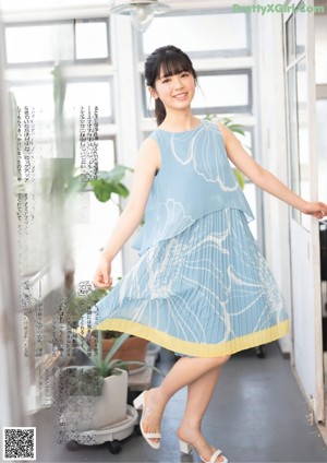 A woman in a blue dress is posing for a magazine.