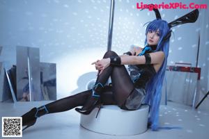 A woman in a black and blue outfit sitting on the floor.