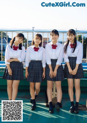 A group of young women standing next to each other on a bridge.