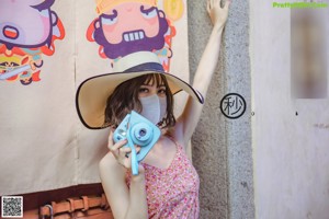 A woman in a pink dress and hat taking a selfie.