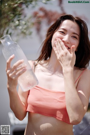 A woman drinking water from a plastic bottle.