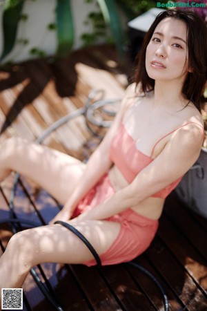 A woman in a pink bikini sitting on a white chair.