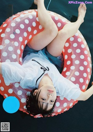 A woman in a polka dot bathing suit leaning against a pole.