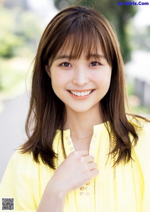 A young woman sitting on the ground with a smile on her face.