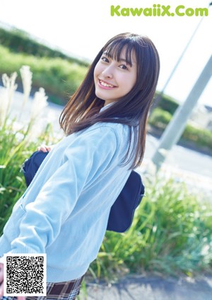 A young woman in a school uniform crouching on the ground.