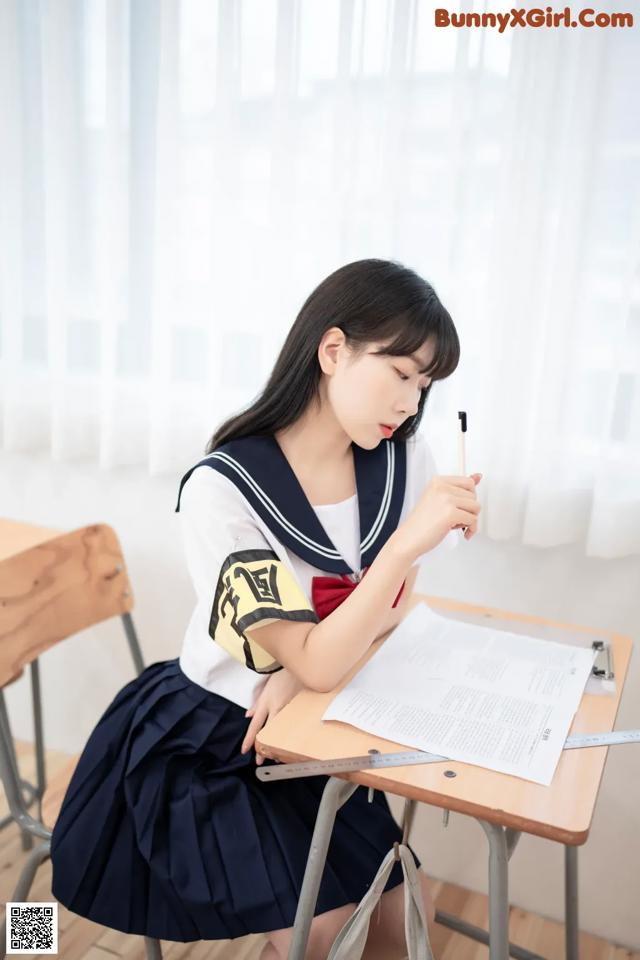 A woman sitting at a desk writing on a piece of paper.