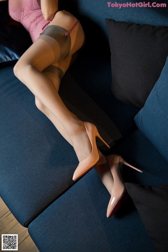 A woman in stockings and high heels laying on a blue couch.