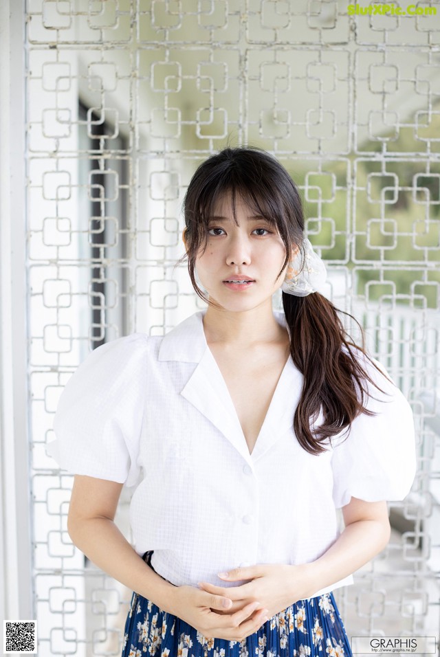 A woman in a white shirt and blue skirt posing for a picture.