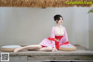 A woman in a red kimono sitting on a wooden bench.