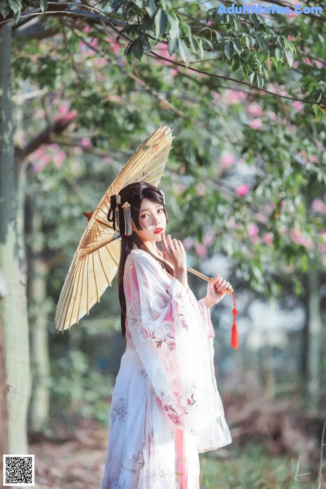 A woman in a white kimono holding an umbrella.