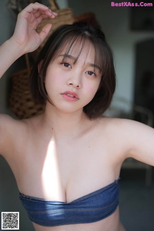 A young woman in a pink bikini sitting on the grass.