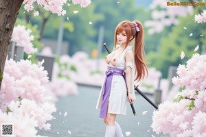 A woman in traditional attire holds a sword, standing outdoors near cherry blossoms and traditional buildings.