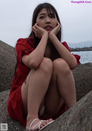 A woman in a red bikini sitting on a wooden platform.