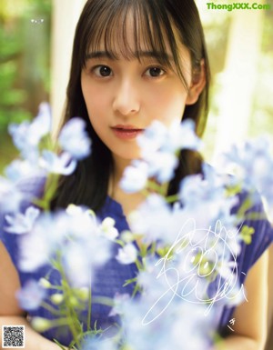 A young woman holding a bunch of blue flowers.