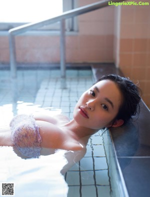 A woman in a bikini sitting on a bed.