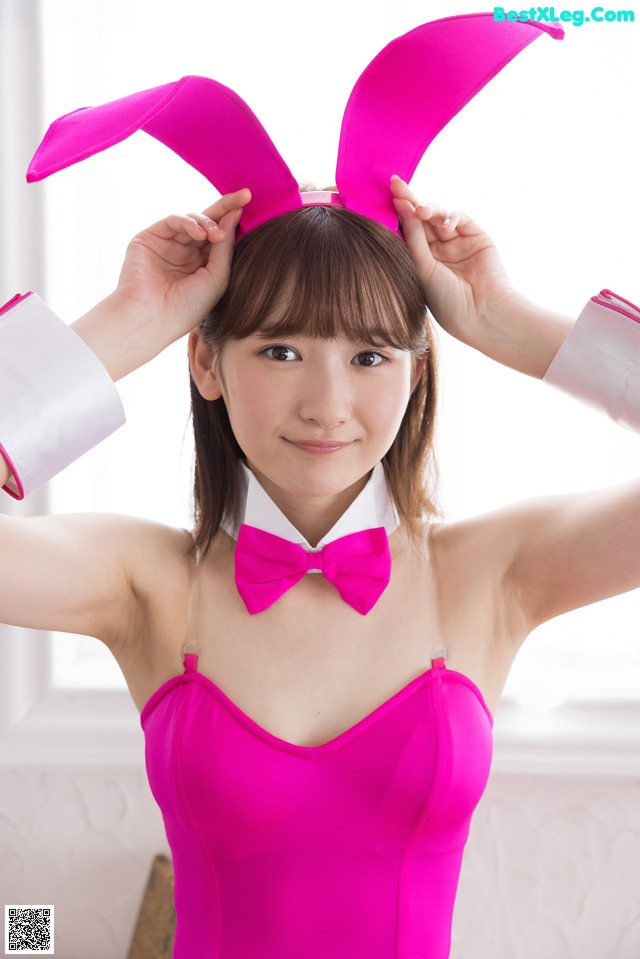 A woman in a pink dress with bunny ears on her head.