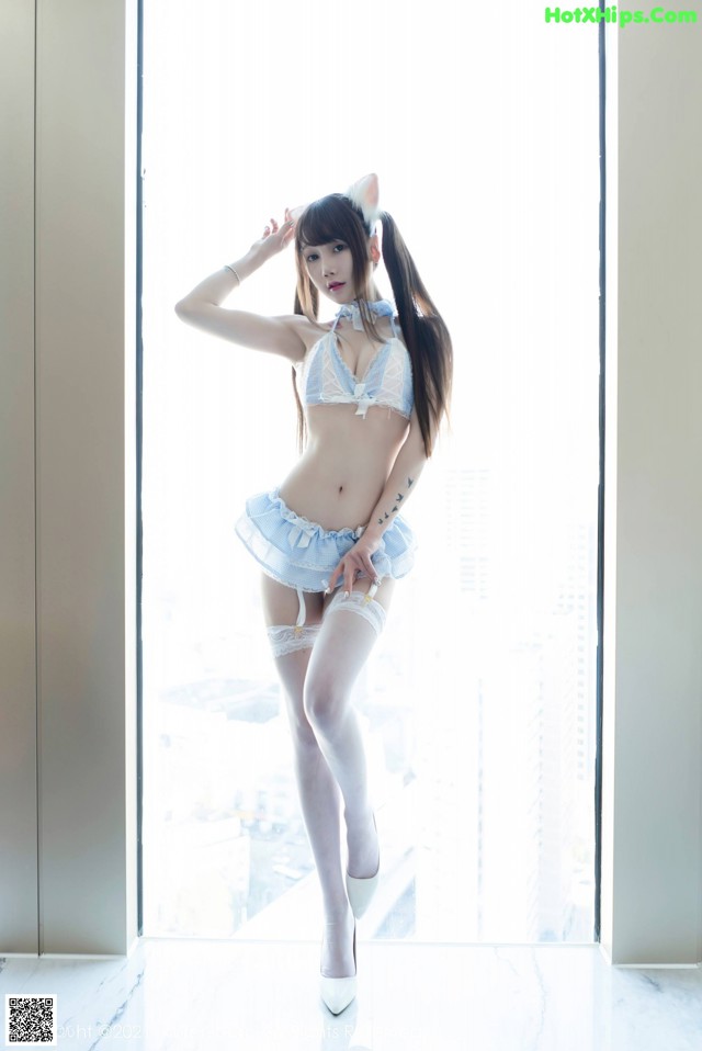A woman in lingerie posing in front of a window.