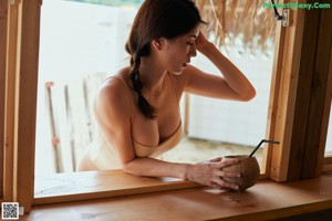 A woman in a beige one piece swimsuit leaning against a wall.