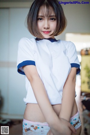 A woman in a white shirt and blue panties posing for a picture.