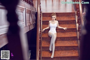 A woman sitting on a set of stairs wearing white stockings.