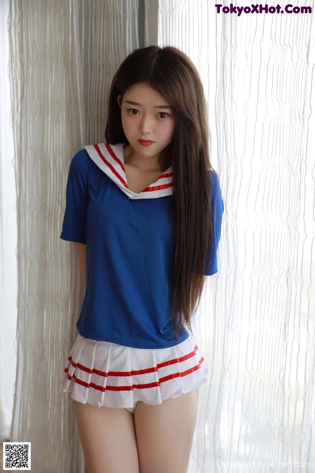 A woman in a blue shirt and white skirt posing for a picture.