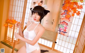 A woman in a white bathing suit sitting on a tatami mat.
